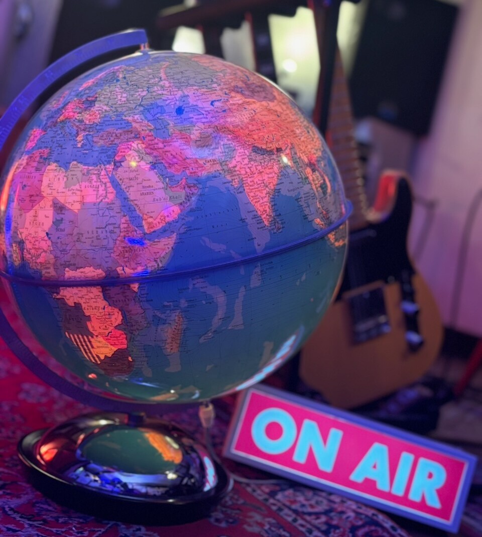 The MojoGlobe - "Der" Globus Ein Foto des Globus im Bandkeller. Daneben ist ein "On Air" Schild - immer in den Livestreams dabei. Im Hintergrund ist eine Gitarre sichtbar.
